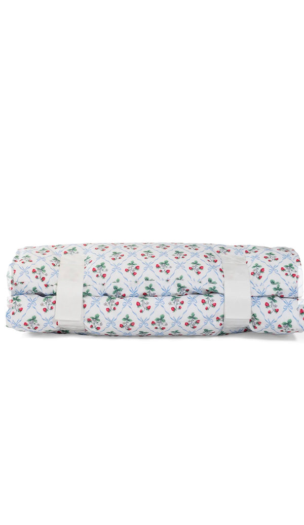 Rolled-up floral nap mat with a white strap on a white background