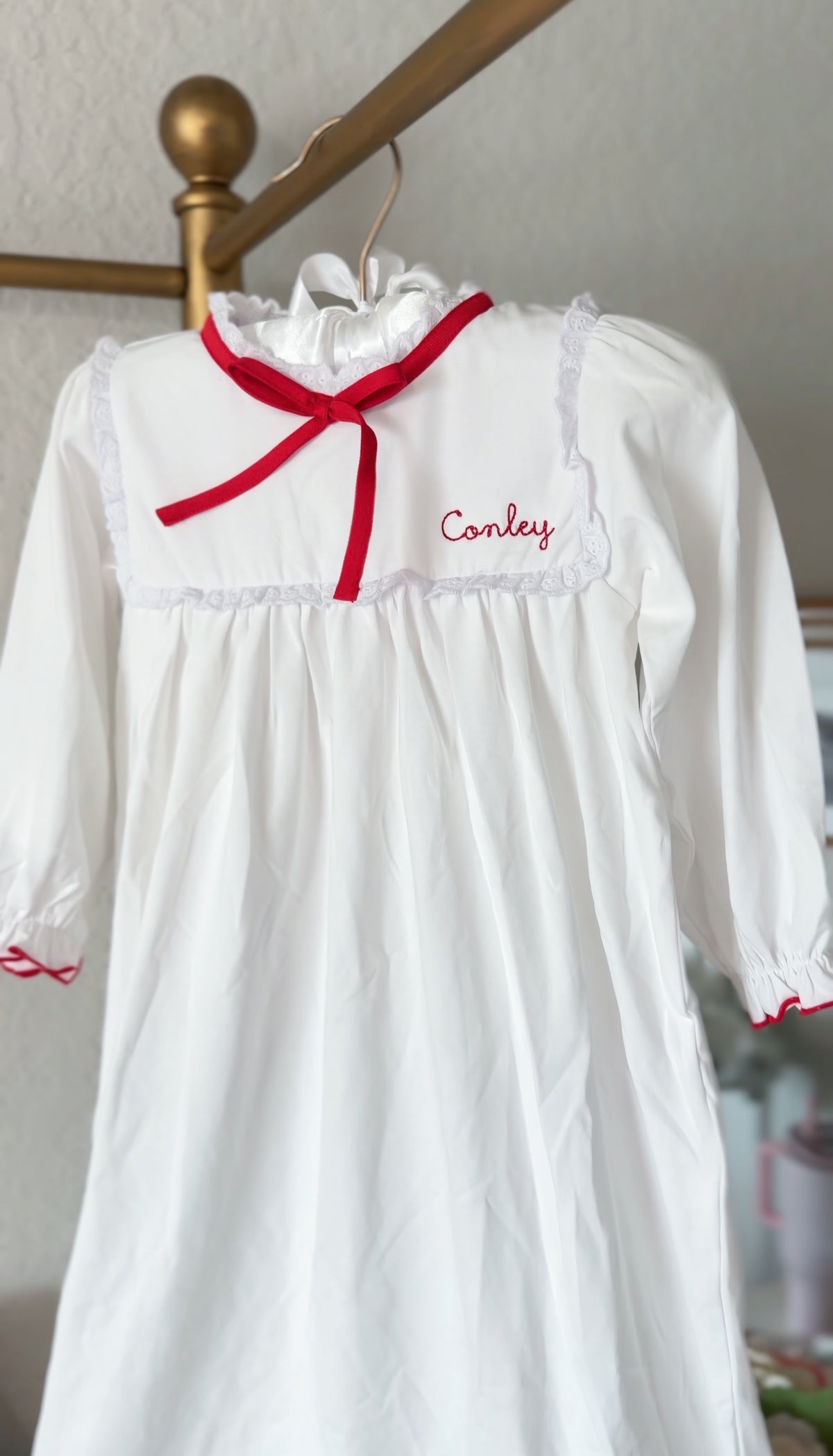 White pima cotton nightgown with red ribbon bow and embroidered name on collar
