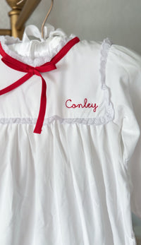 White pima cotton nightgown with red ribbon tie and 'Conley' embroidered on the collar