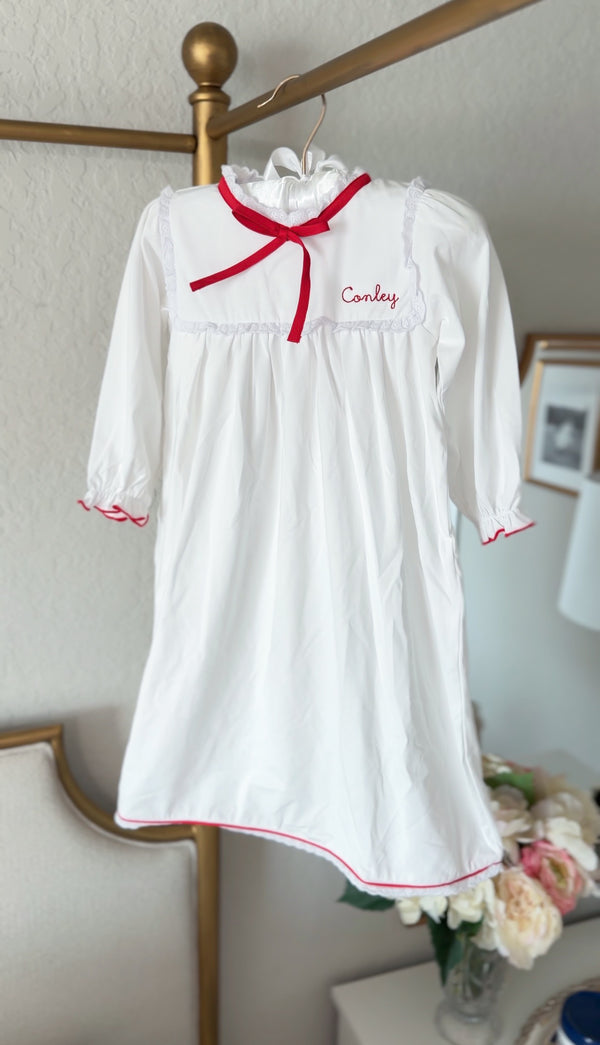 White pima cotton nightgown with red ribbon bow, hanging with embroidered name