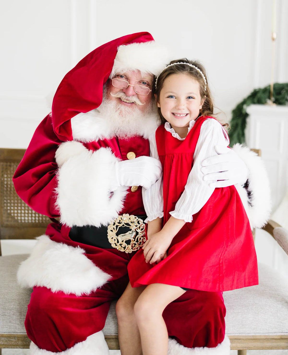 Girl in red corduroy dress with white puff-sleeve blouse sitting with Santa
