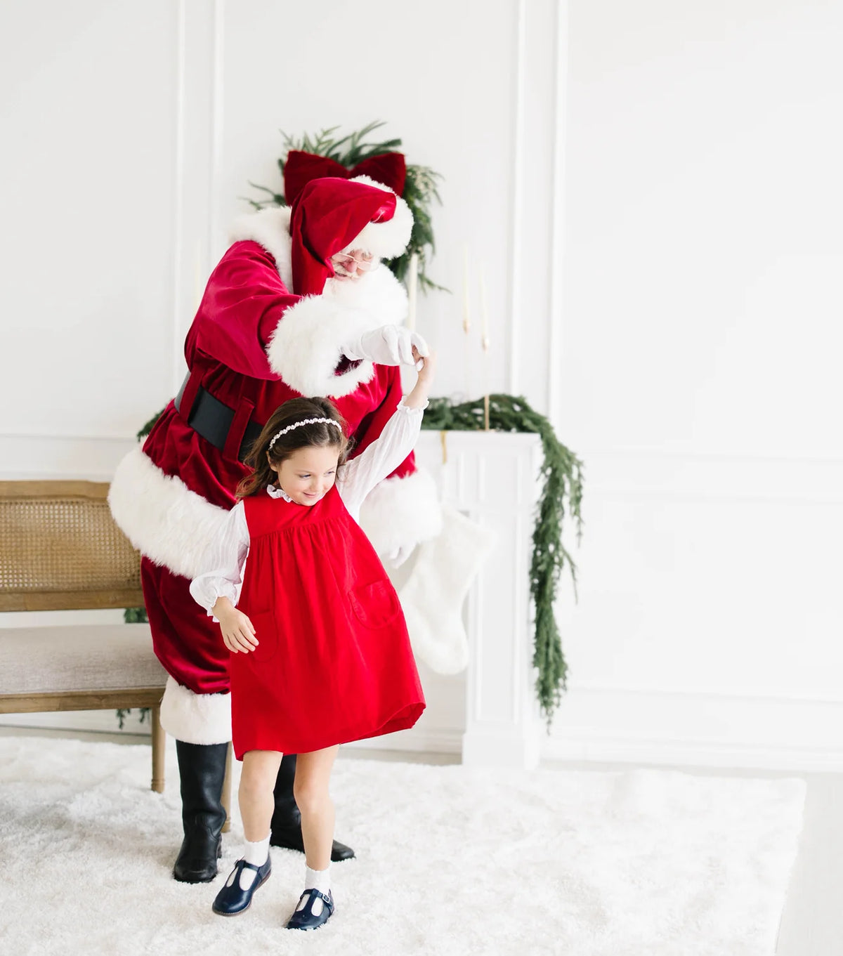 Girl in red corduroy dress twirling with Santa in the background
