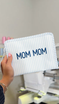 Blue and white striped TRVL Roadie pouch embroidered with 'MOM MOM' in navy lettering
