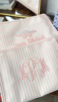 Pink Pimlico stripe TRVL Roadie pouches, one embroidered with a dinosaur design and name, the other with 'MRM' monogram