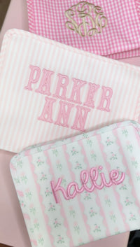 Pink Pimlico stripe TRVL Roadie pouch embroidered with 'PARKER ANN' in block letters, shown with other monogrammed pouches