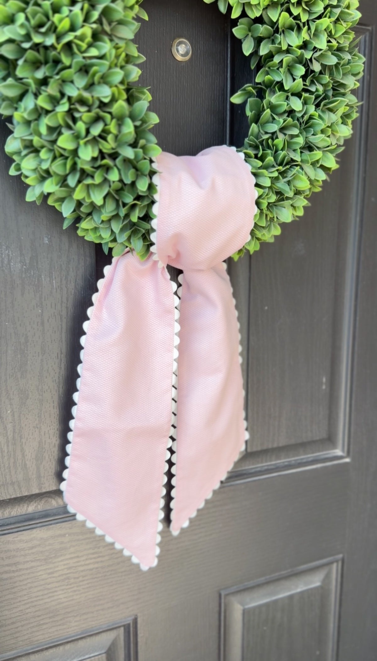 Green wreath with a pink bow on a gray door