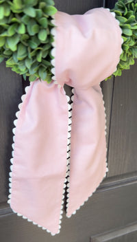 Pink decorative bow on a door with greenery