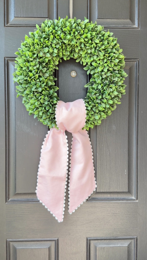 Green wreath with a pink bow on a gray door