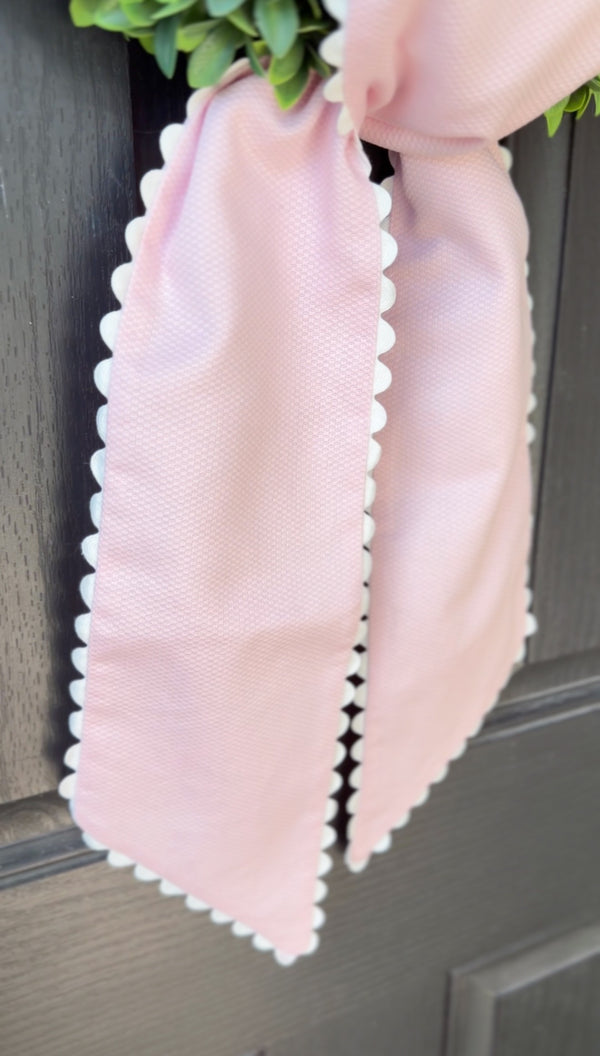 Pink decorative bow with scalloped edges on a door
