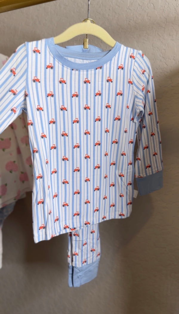 Children's pajama set with tractor pattern on a hanger against a neutral background