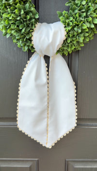 White wreath with a white bow on a dark surface