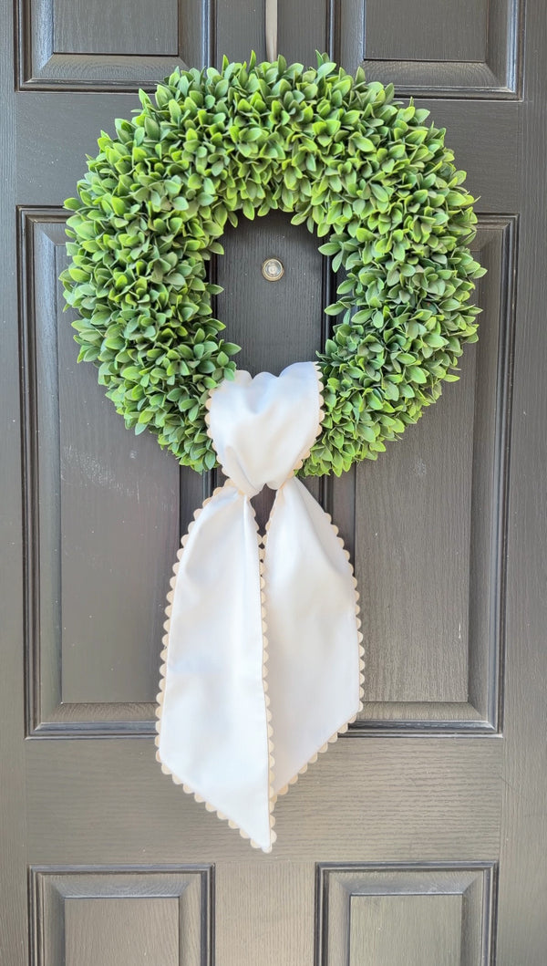 Green wreath with a white bow on a gray door