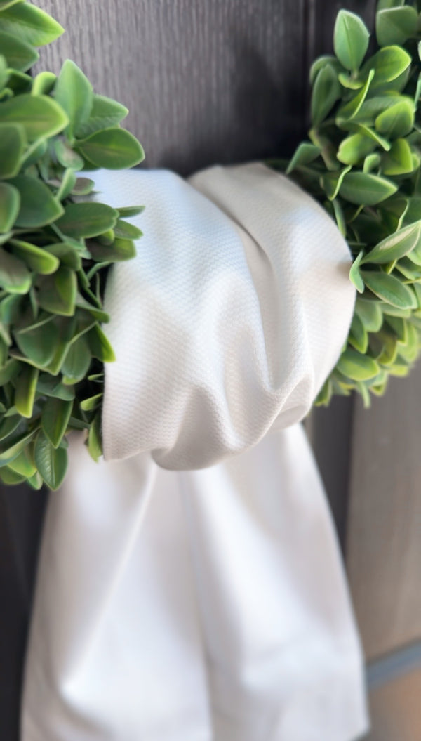 Green wreath with white ribbon on a plain background