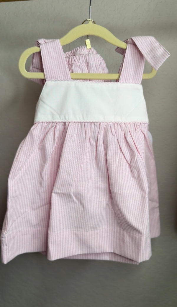 Pink and white dress on a hanger against a plain background