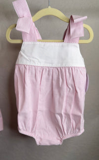 Pink and white striped baby romper on a hanger against a gray background