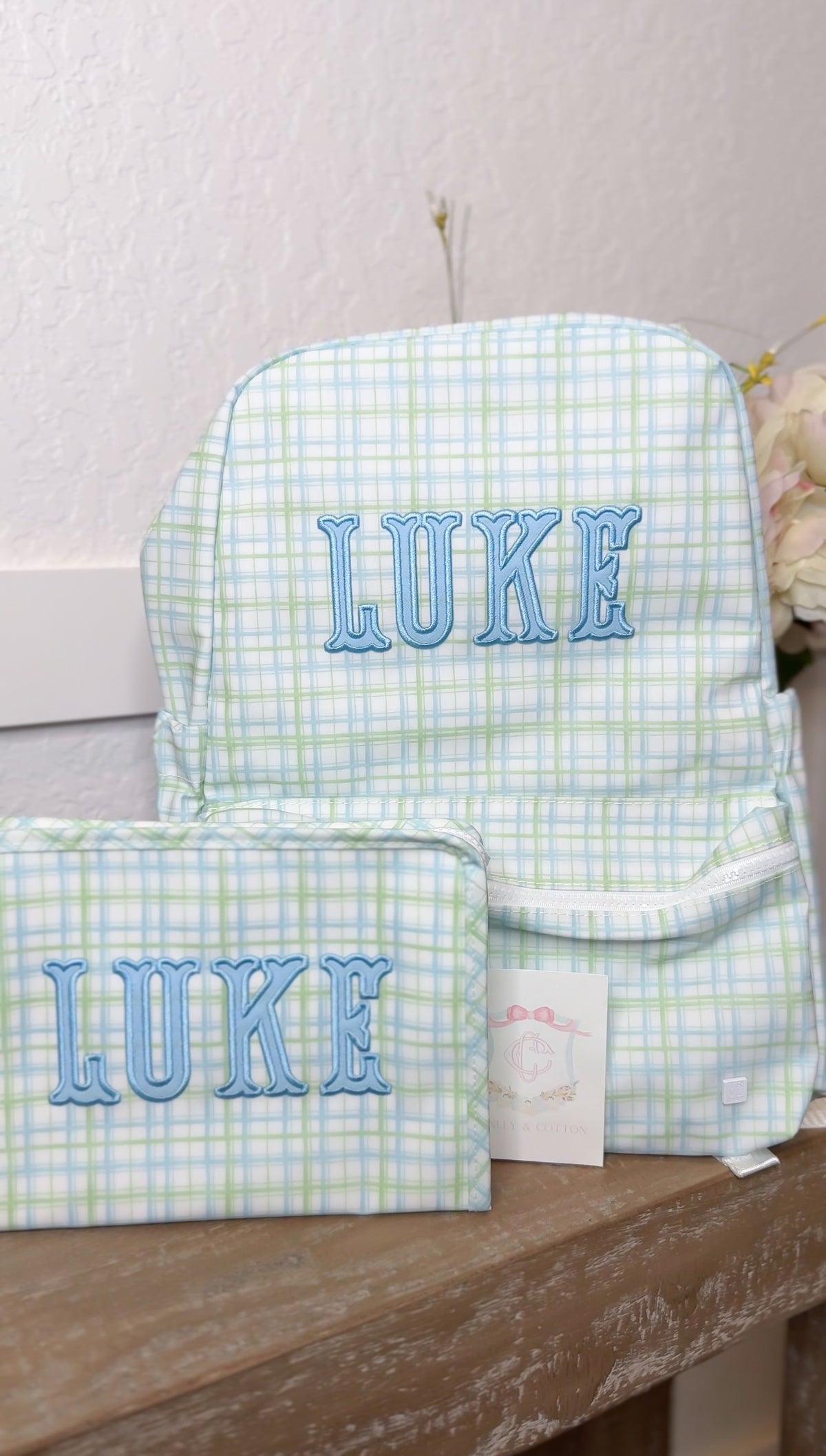 Green and blue plaid TRVL backpack and pouch both embroidered with the name 'Luke'