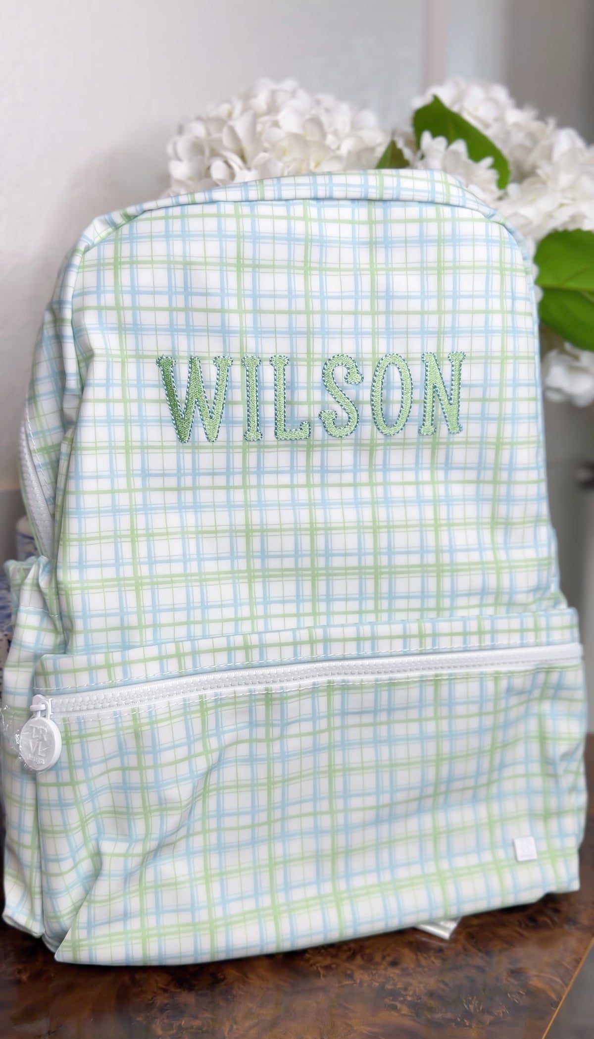Green and blue plaid TRVL Backpacker embroidered with the name 'Wilson'