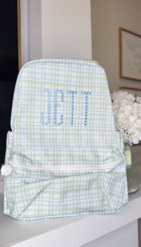 Green and blue plaid TRVL Backpacker embroidered with the beaded name 'Jett'