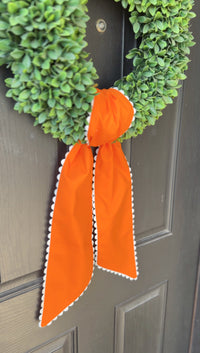 Green wreath with an orange ribbon on a door