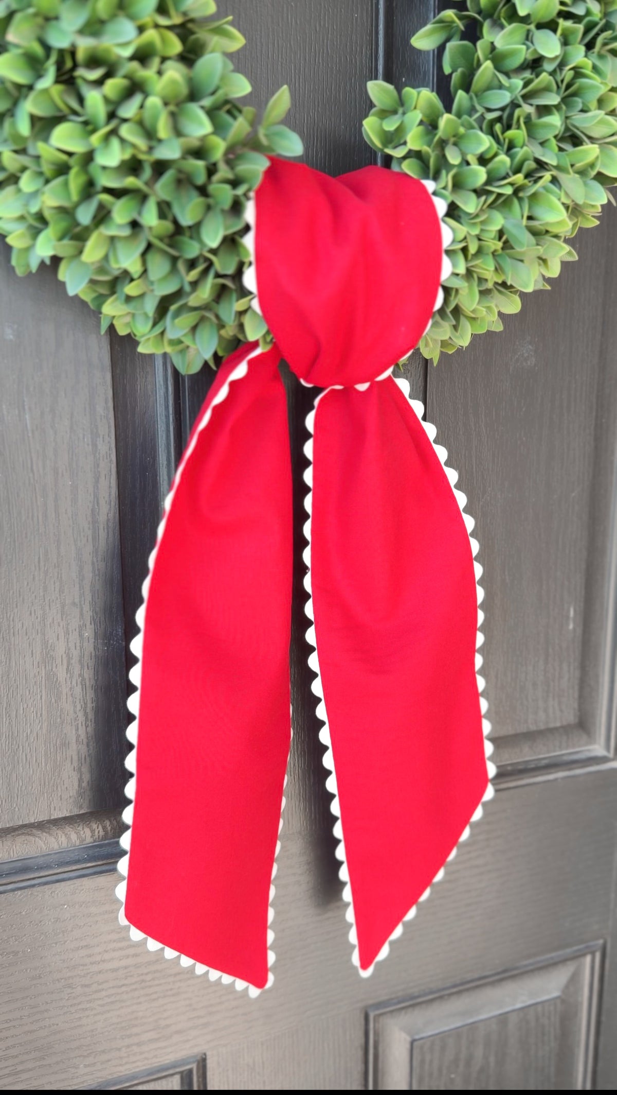 Red wreath sash with white trim on a gray door