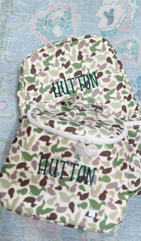 Camo duck print TRVL Backpacker and pouch both embroidered with the name 'Hutton'