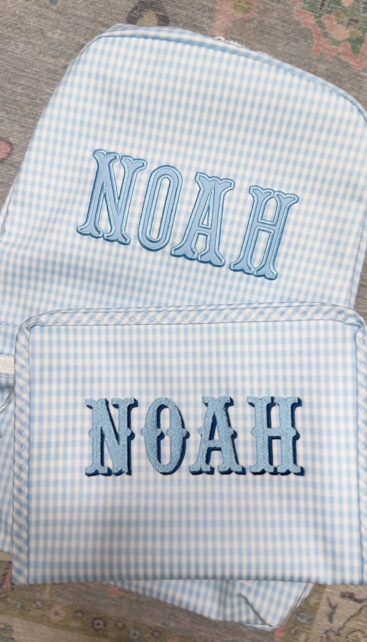 Light blue gingham TRVL Backpacker and pouch both embroidered with the name 'Noah'