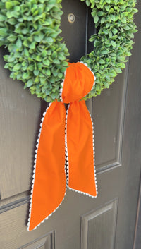 Green wreath with an orange ribbon on a door
