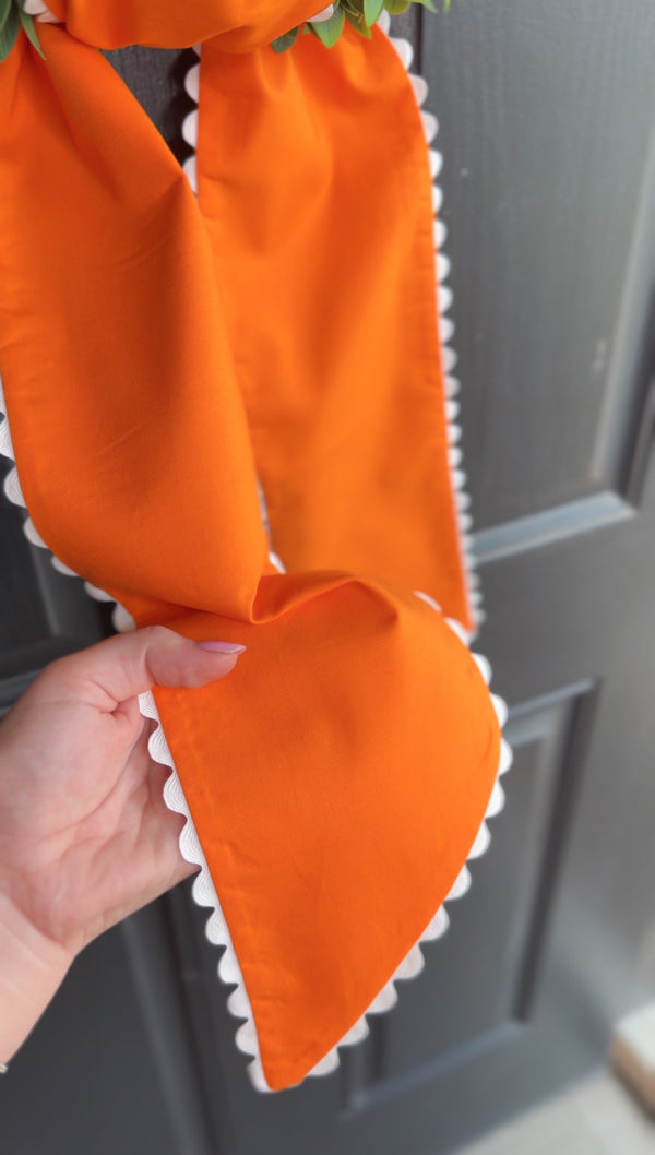 Orange fabric with white trim held against a gray door