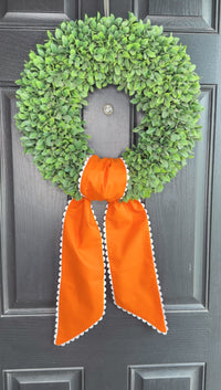 Green wreath with an orange ribbon on a dark surface