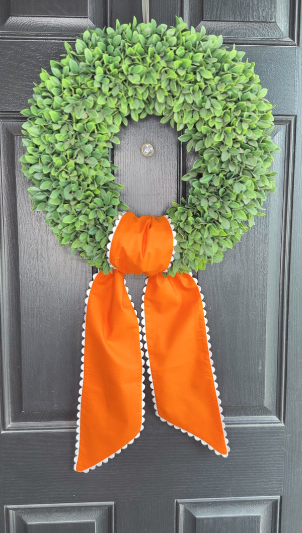 Green wreath with an orange ribbon on a dark surface