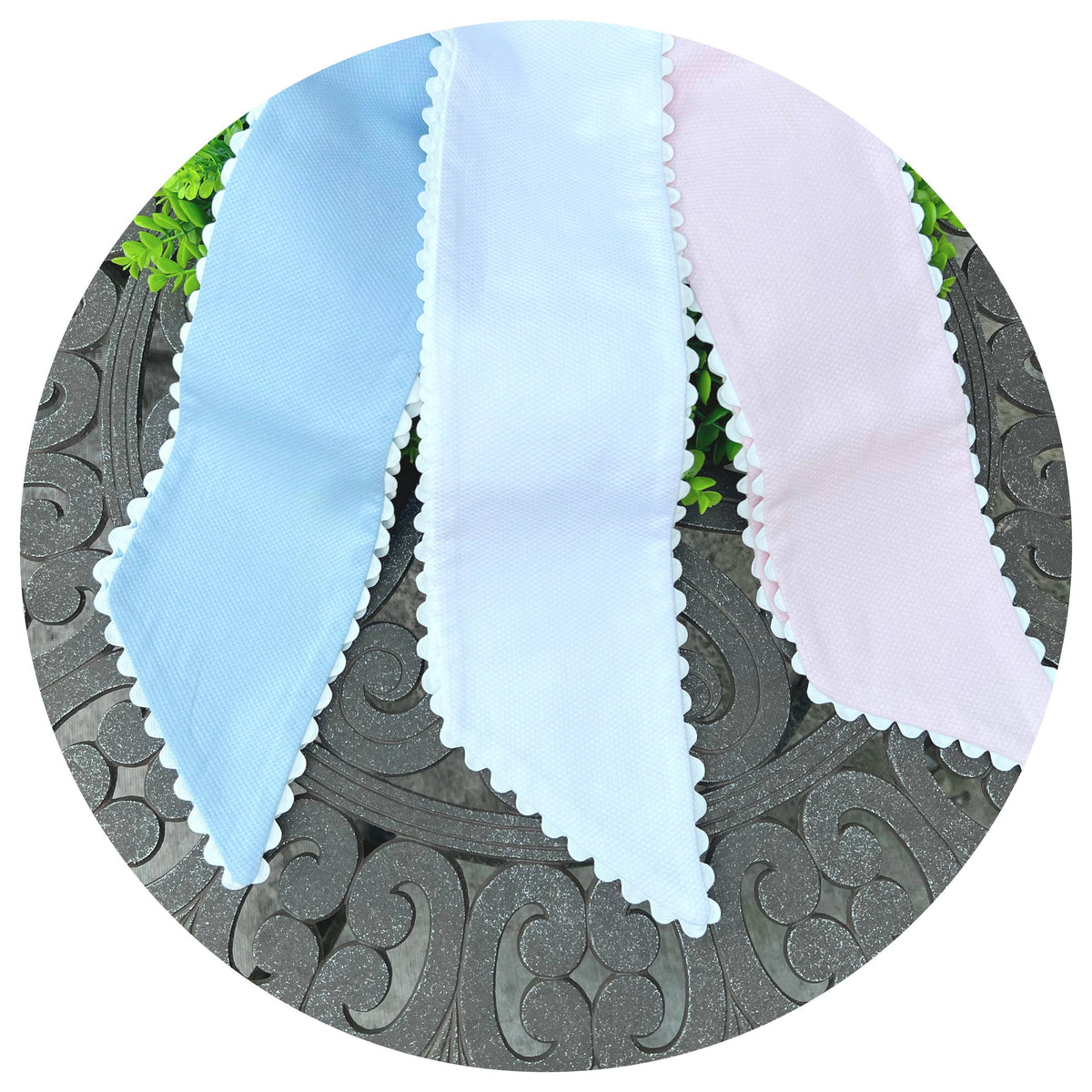 Three cotton pique sash tails in light blue, white, and pink laid side by side, each with white scalloped trim
