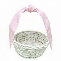 Pale pink cotton pique sash tied in a bow on the handle of a white wicker basket, plain background