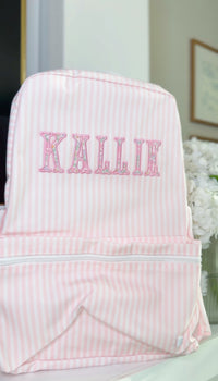 Pink and white striped backpack embroidered with the name 'Kallie' in a floral applique font