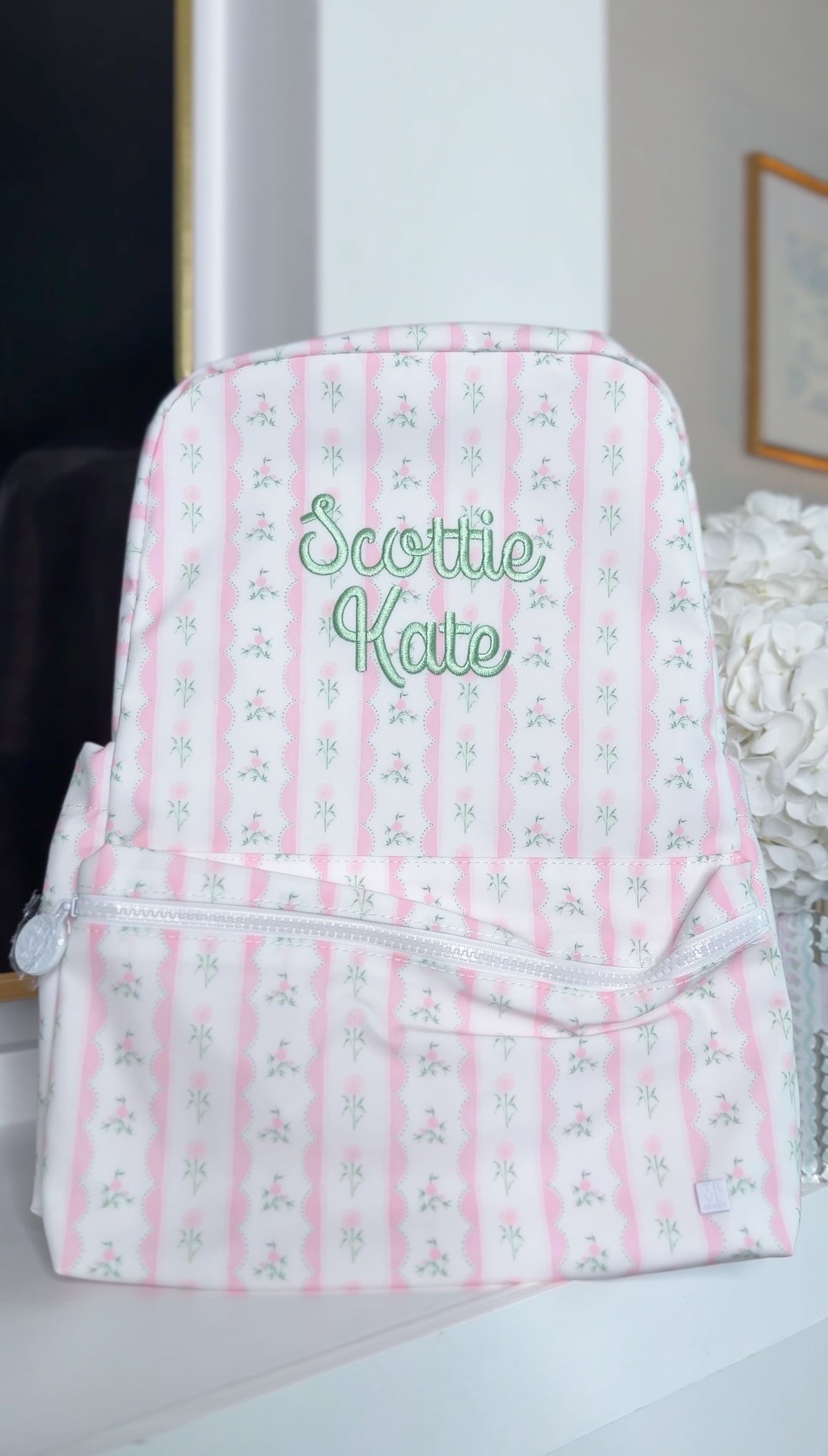 White backpack with pink and green ribbon floral stripe print, embroidered 'Scottie Kate' in green script on the front