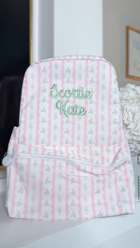 White backpack with pink and green ribbon floral stripe print, embroidered 'Scottie Kate' in green script on the front