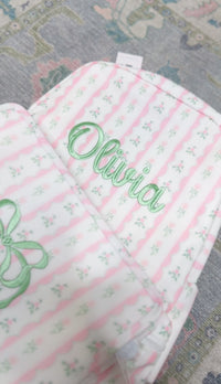 Pink ribbon floral striped bag embroidered with the name 'Olivia' in green script and a green bow design