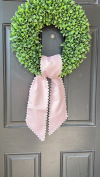 Green wreath with a pink bow on a gray door