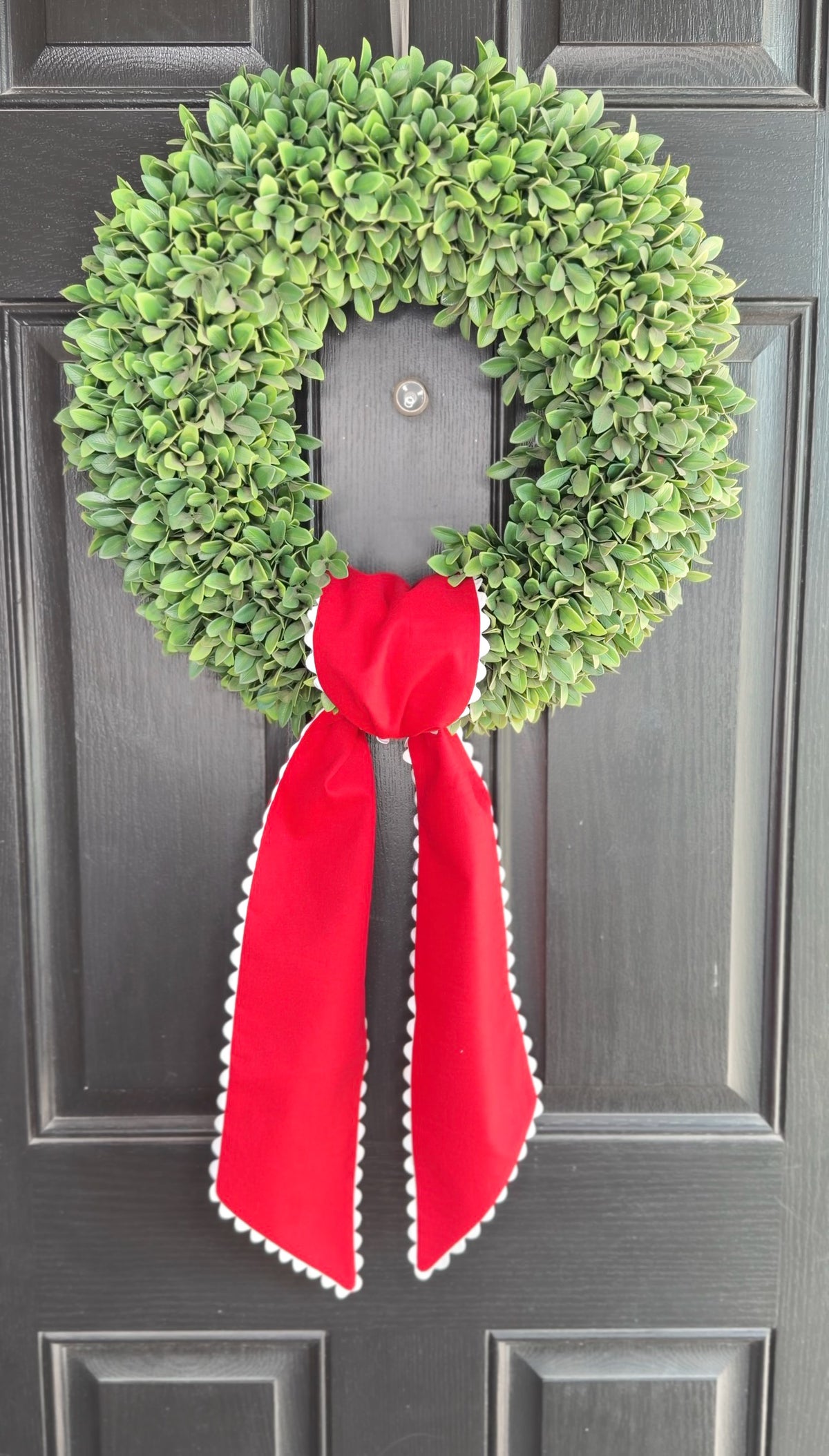 Green wreath with a red ribbon on a gray door