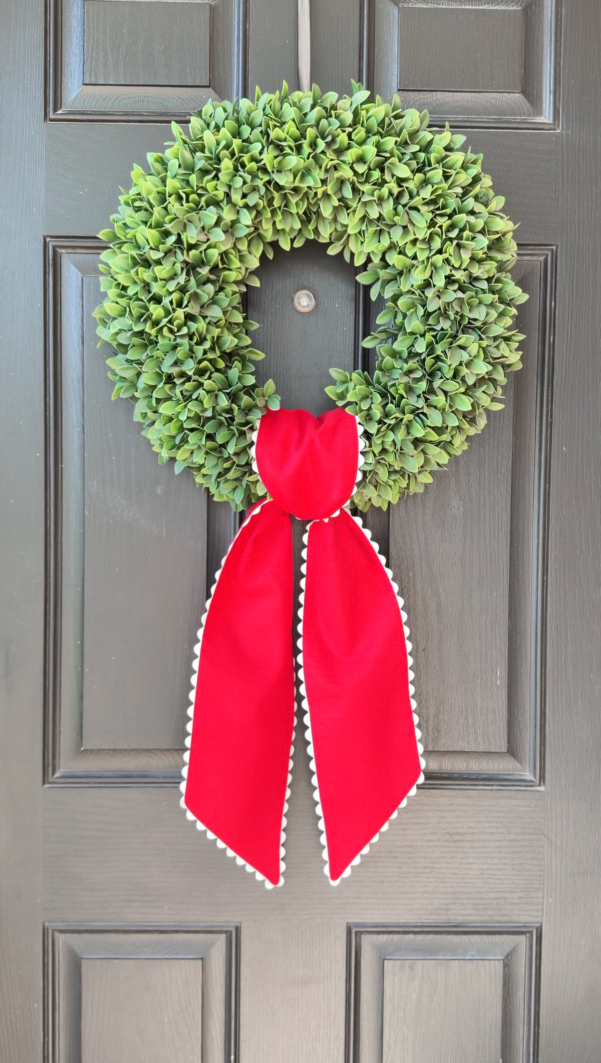 Green wreath with a red ribbon on a gray door