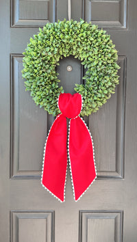 Green wreath with a red ribbon on a gray door