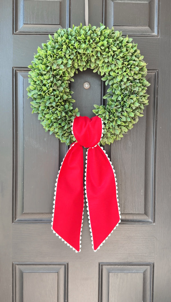 Green wreath with a red ribbon on a gray door