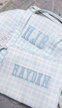 Light blue plaid TRVL bag and pouch embroidered with the 'HJB' monogram and the name 'Hayden'