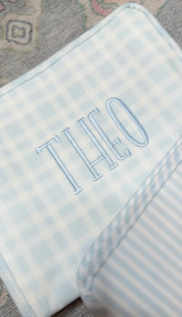 Light blue plaid TRVL pouch embroidered with the name 'Theo'