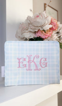 Light blue gingham TRVL pouch embroidered with the pink 'EKG' monogram