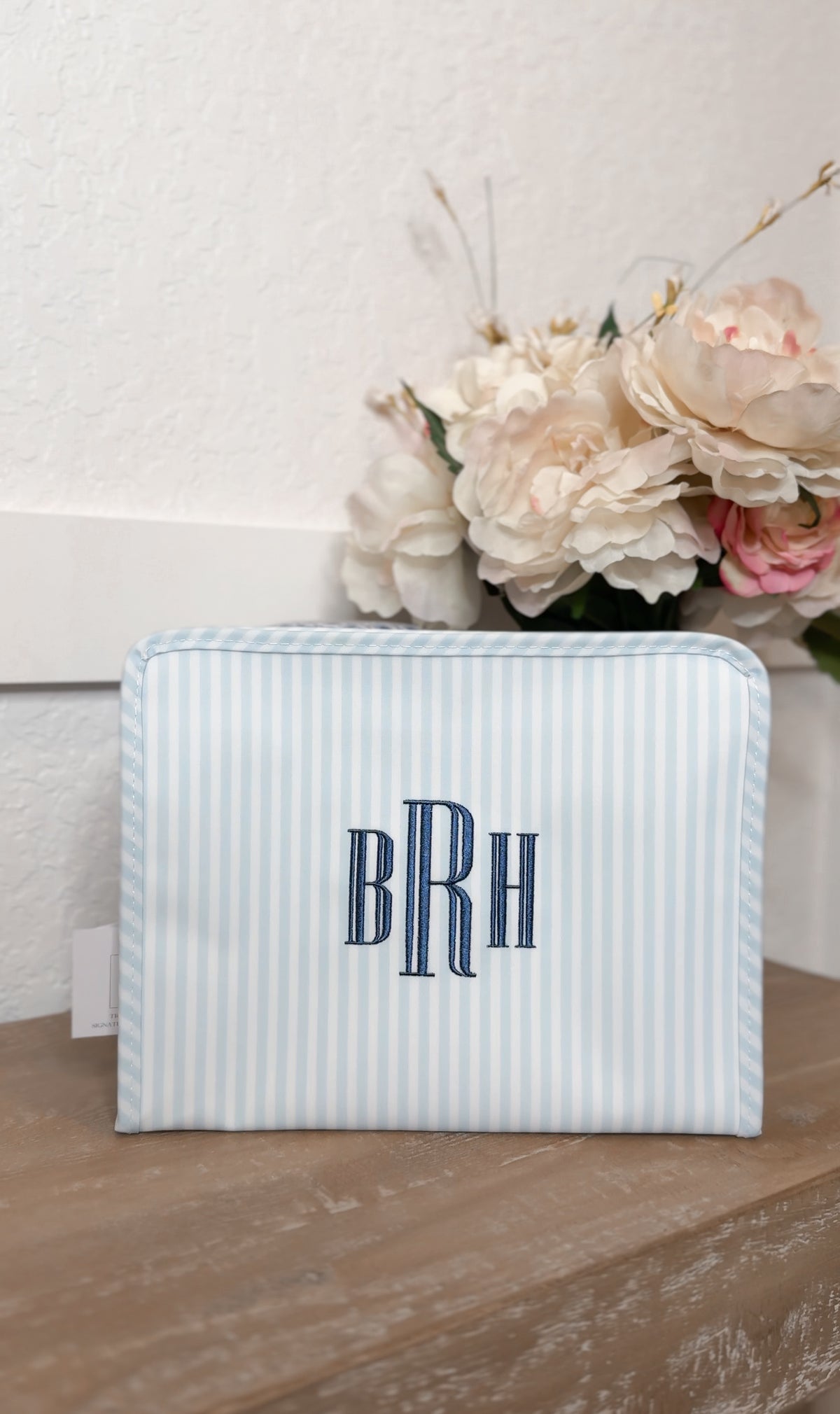 Blue and white striped TRVL Roadie pouch embroidered with 'BRH' monogram in navy serif letters