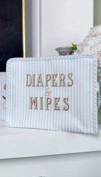 Blue and white striped TRVL Roadie pouch embroidered with 'Diapers & Wipes' in gold lettering
