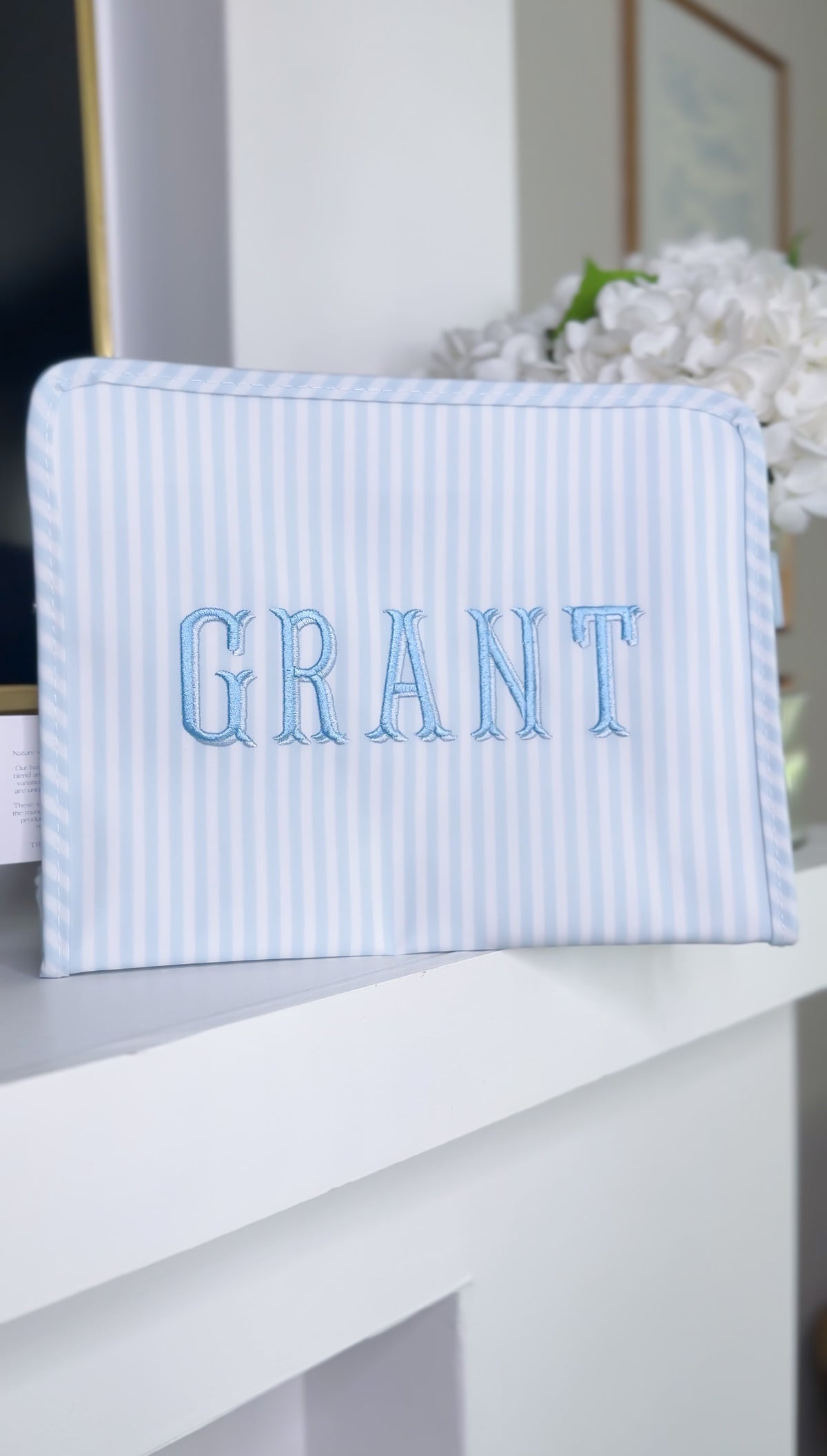Blue and white striped TRVL Roadie pouch embroidered with 'GRANT' in outlined serif letters