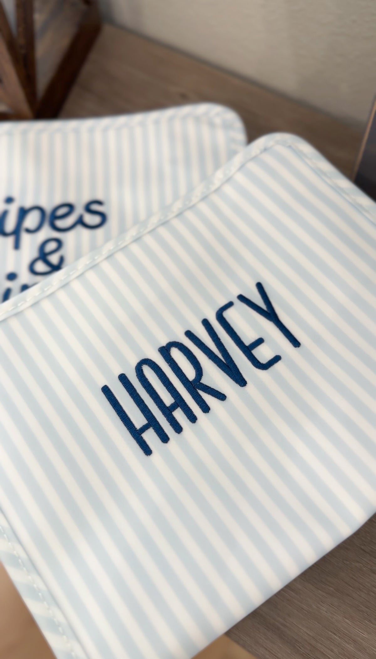 Blue and white striped TRVL Roadie pouch embroidered with 'HARVEY' in navy handwritten-style lettering