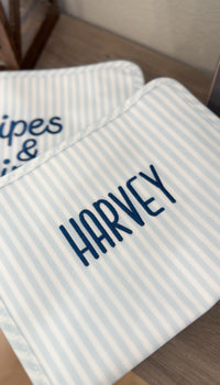 Blue and white striped TRVL Roadie pouch embroidered with 'HARVEY' in navy handwritten-style lettering