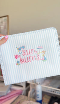 Blue and white striped TRVL Roadie pouch embroidered with 'Sun Bums' and beach icons
